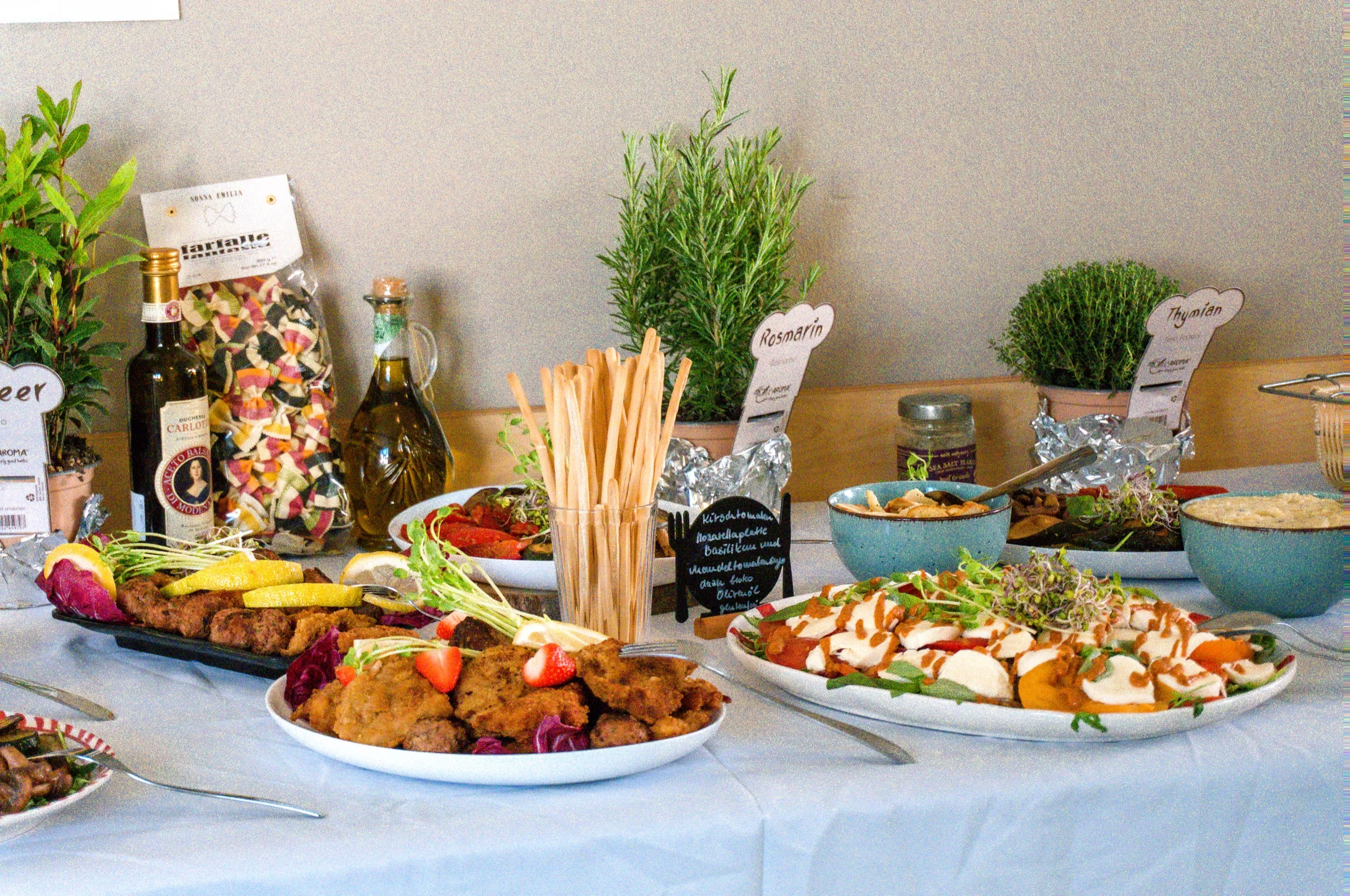 Buffettafel mit Antipasti-Platten, Grissini und Kräutertöpfen